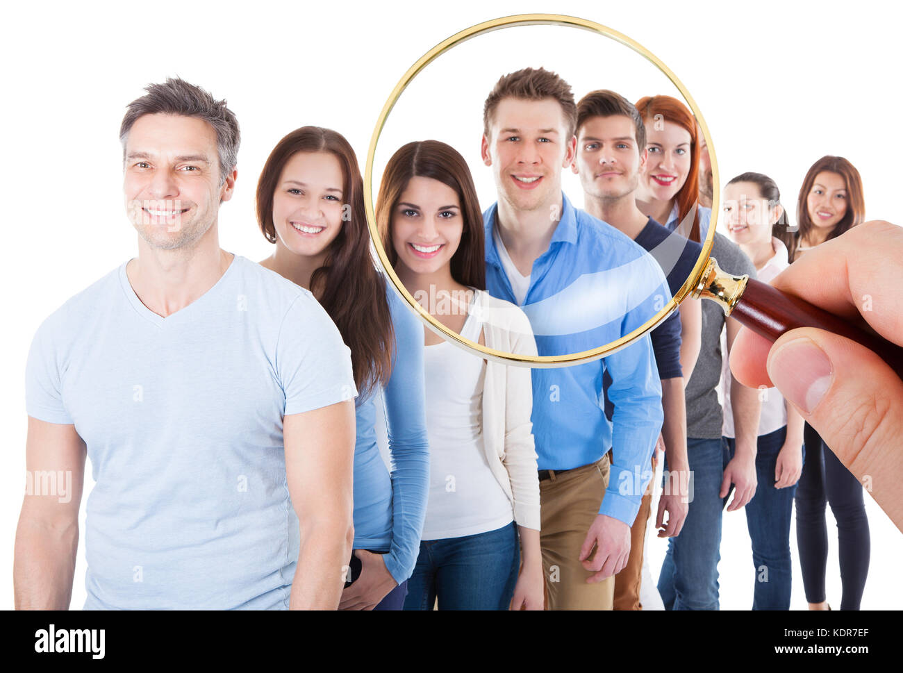 Persona mano che tiene la lente di ingrandimento su un ampio gruppo di felici le persone in piedi in linea su sfondo bianco Foto Stock