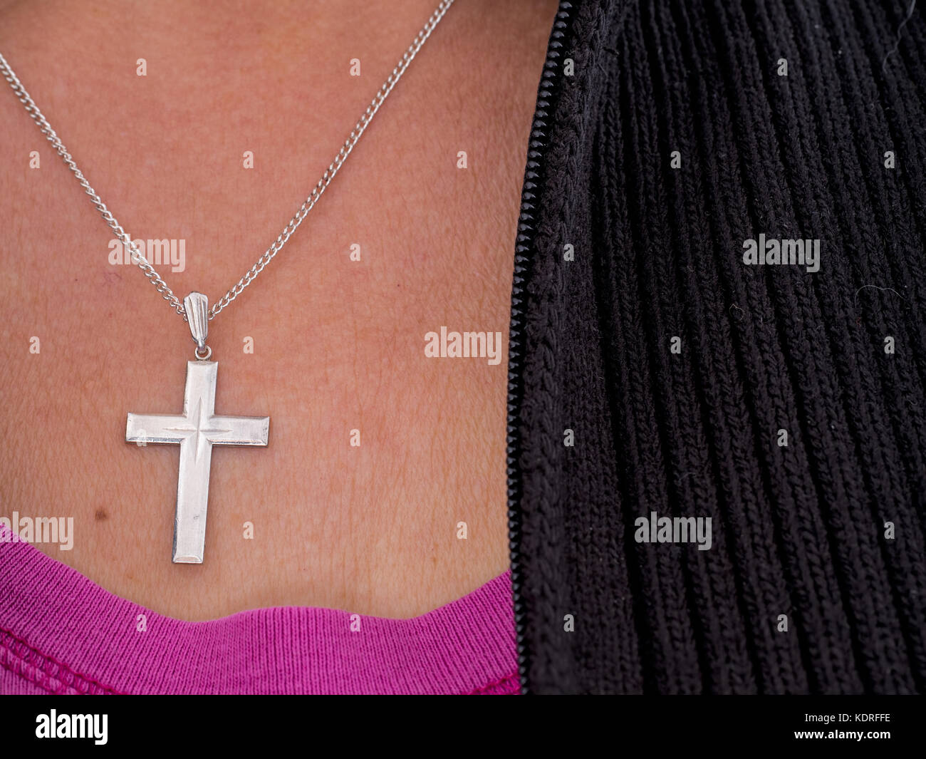 Donna con la croce e la catena, argento. vestiti informali, simbolo religioso. Foto Stock