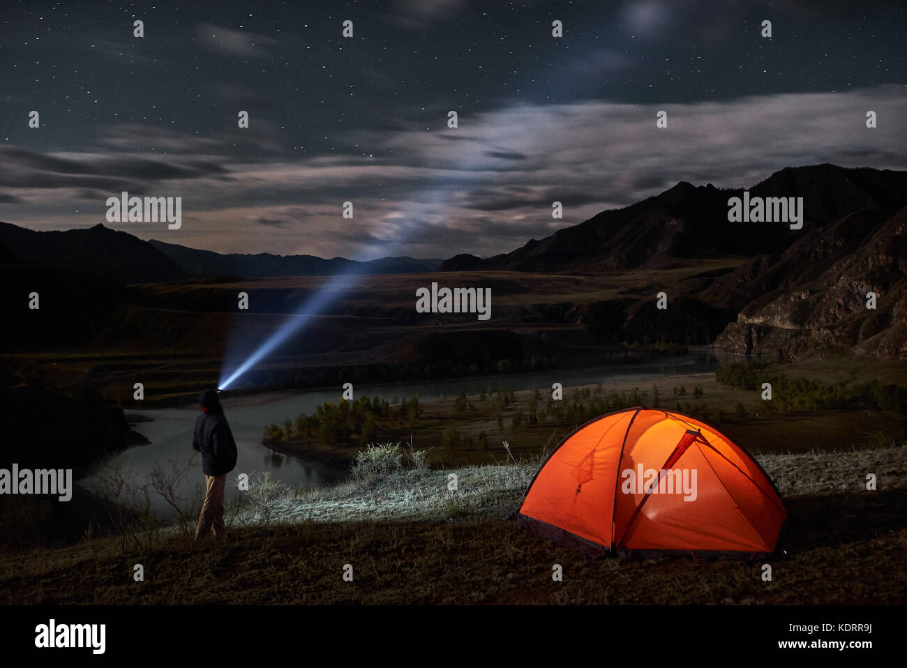 Turismo a maschio con la torcia elettrica vicino al suo accampamento tenda a notte. Foto Stock