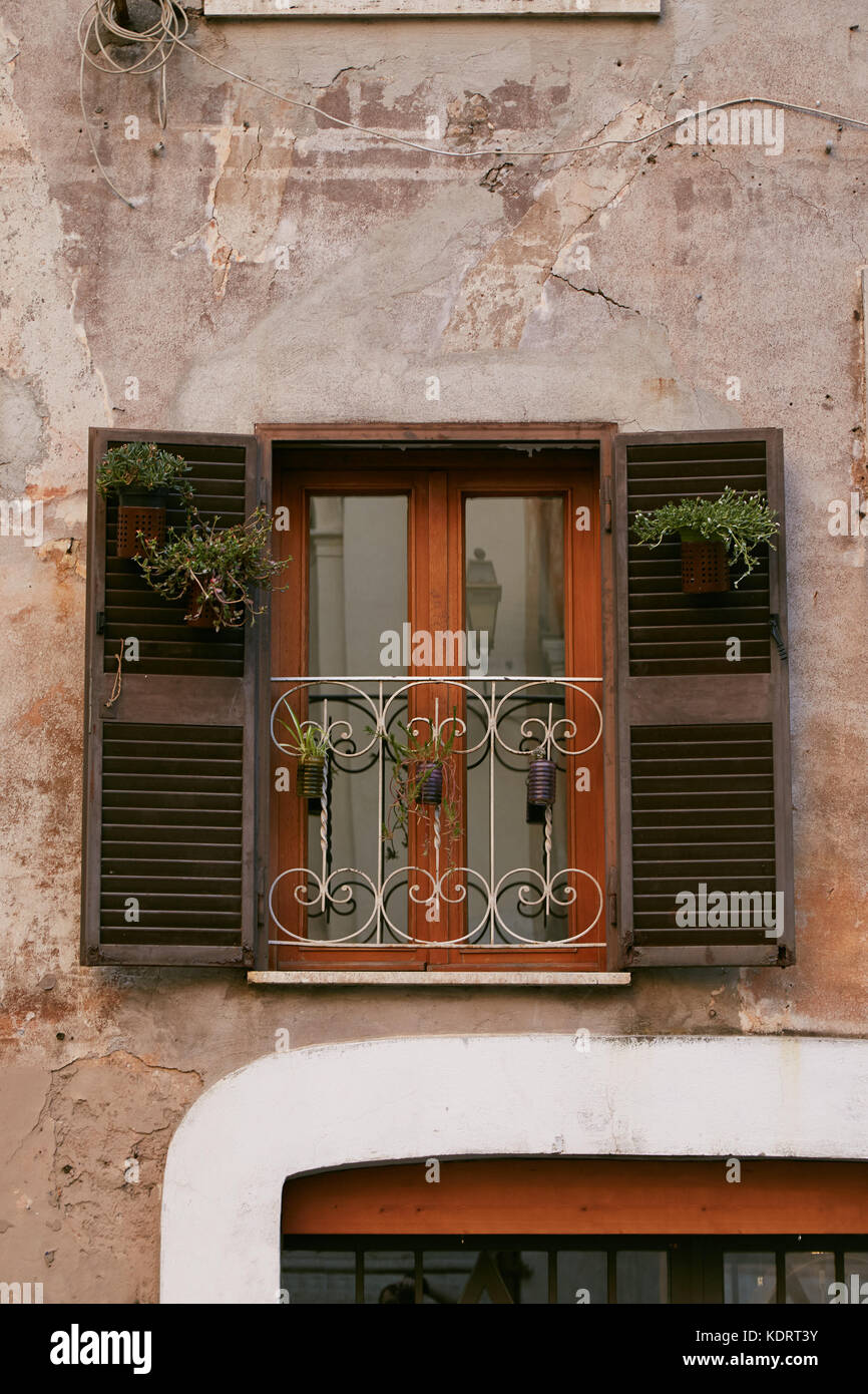 Vecchia finestra con ante aperte decorate con fiori nel cuore di Trastevere  a Roma, Italia Foto stock - Alamy