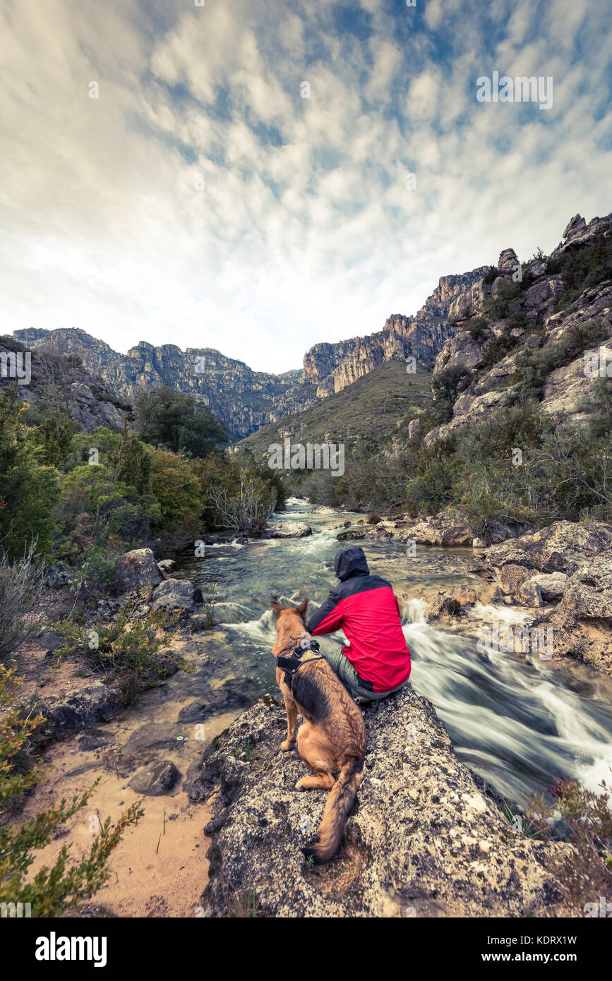 Wanderlust uomo e cane in wild montagne dal fiume. Foto Stock