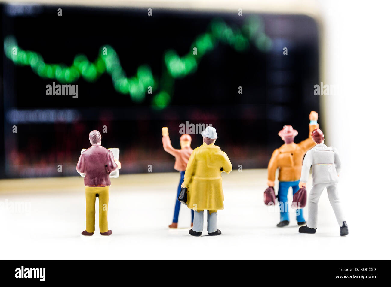 Il concetto di business, primo piano delle figurine in miniatura di uomini di affari in piedi di fronte a grande schermo sfocati con prezzo di stock market grafico con indicatore Foto Stock