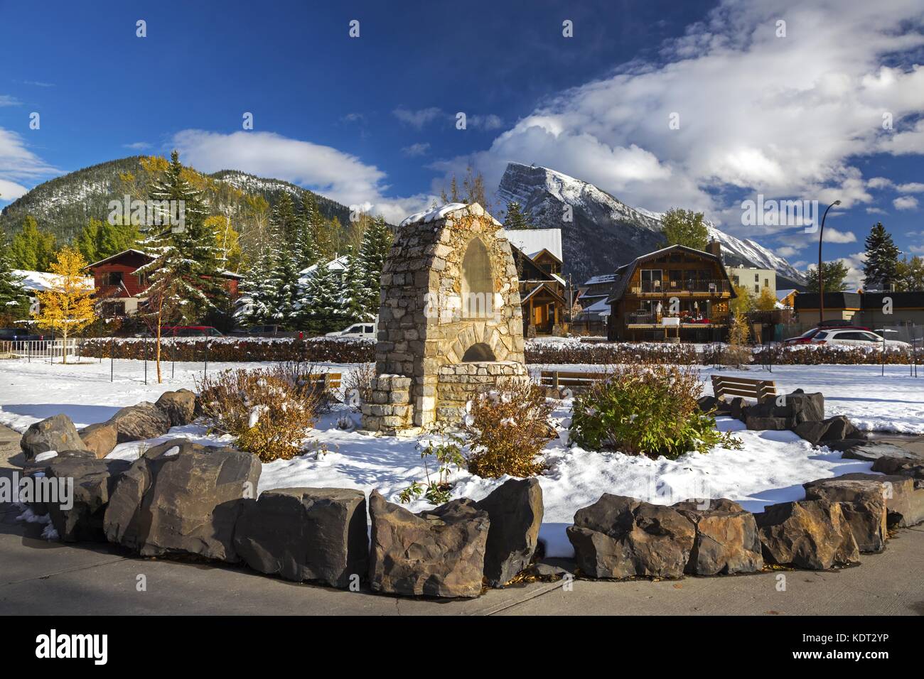 Stone Rock Monument St Mary Catholic Church Courtyard. Cime innevate di Rocky Mountain Peaks Skyline Banff Town National Park Canadian Rockies Alberta Foto Stock