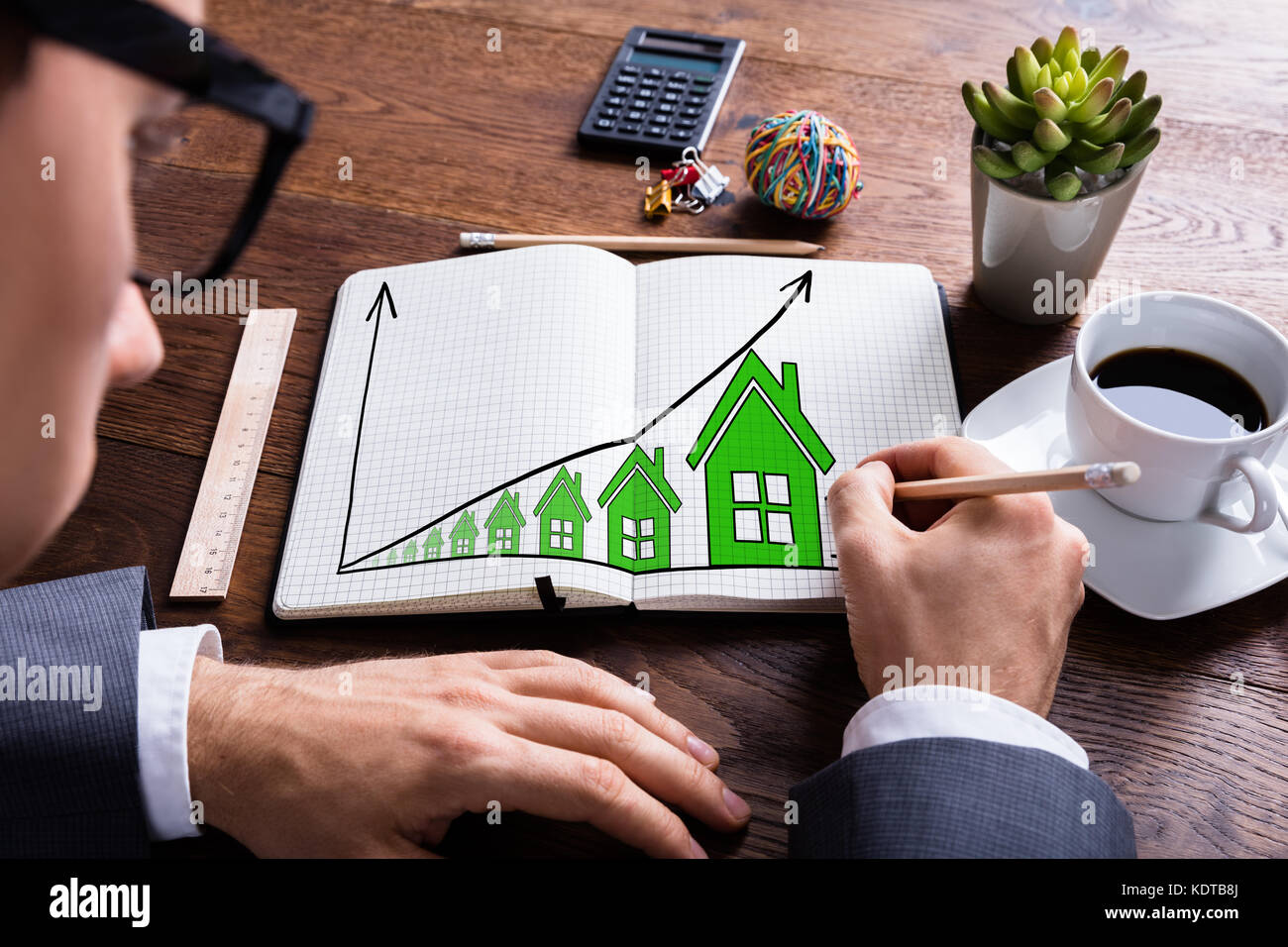 Primo piano di business disegno di crescita in immobili Prezzi in notebook su legno scrivania Foto Stock