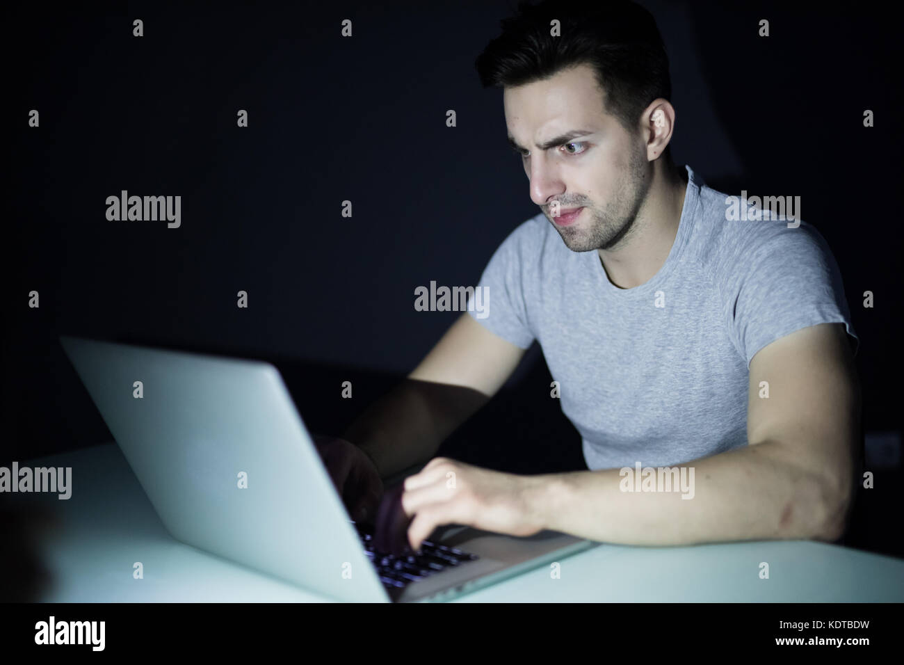 La notte la dipendenza da internet o lavora fino a tardi Uomo con laptop ad una scrivania nel buio Foto Stock