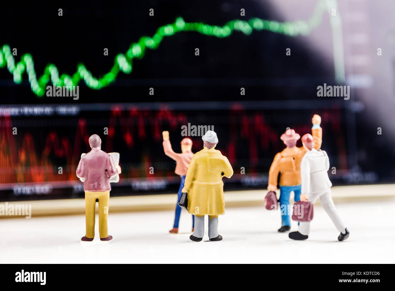 Il concetto di business, primo piano delle figurine in miniatura di uomini di affari in piedi di fronte a grande schermo sfocati con prezzo di stock market grafico con indicatore Foto Stock