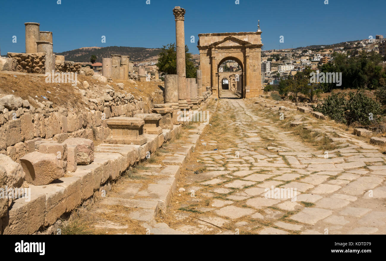 Lastricata Cardo cercando di porta nord e unico permanente di colonne corinzie, città romana di Jerash, antica Gerasa, sito archeologico, Giordania, Medio Oriente Foto Stock