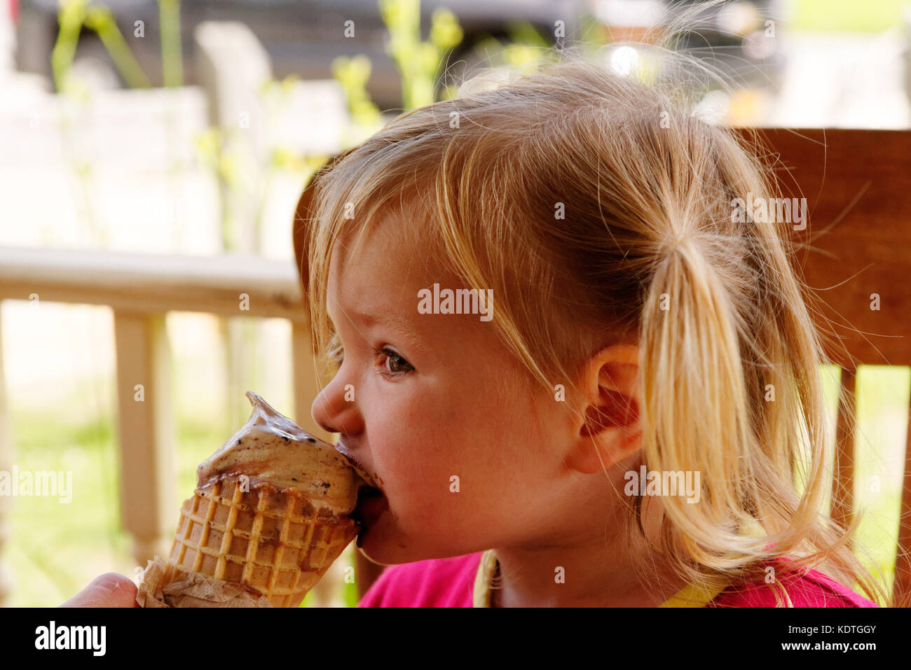 Una bambina di 3 anni di mangiare un gelato al cioccolato Foto Stock