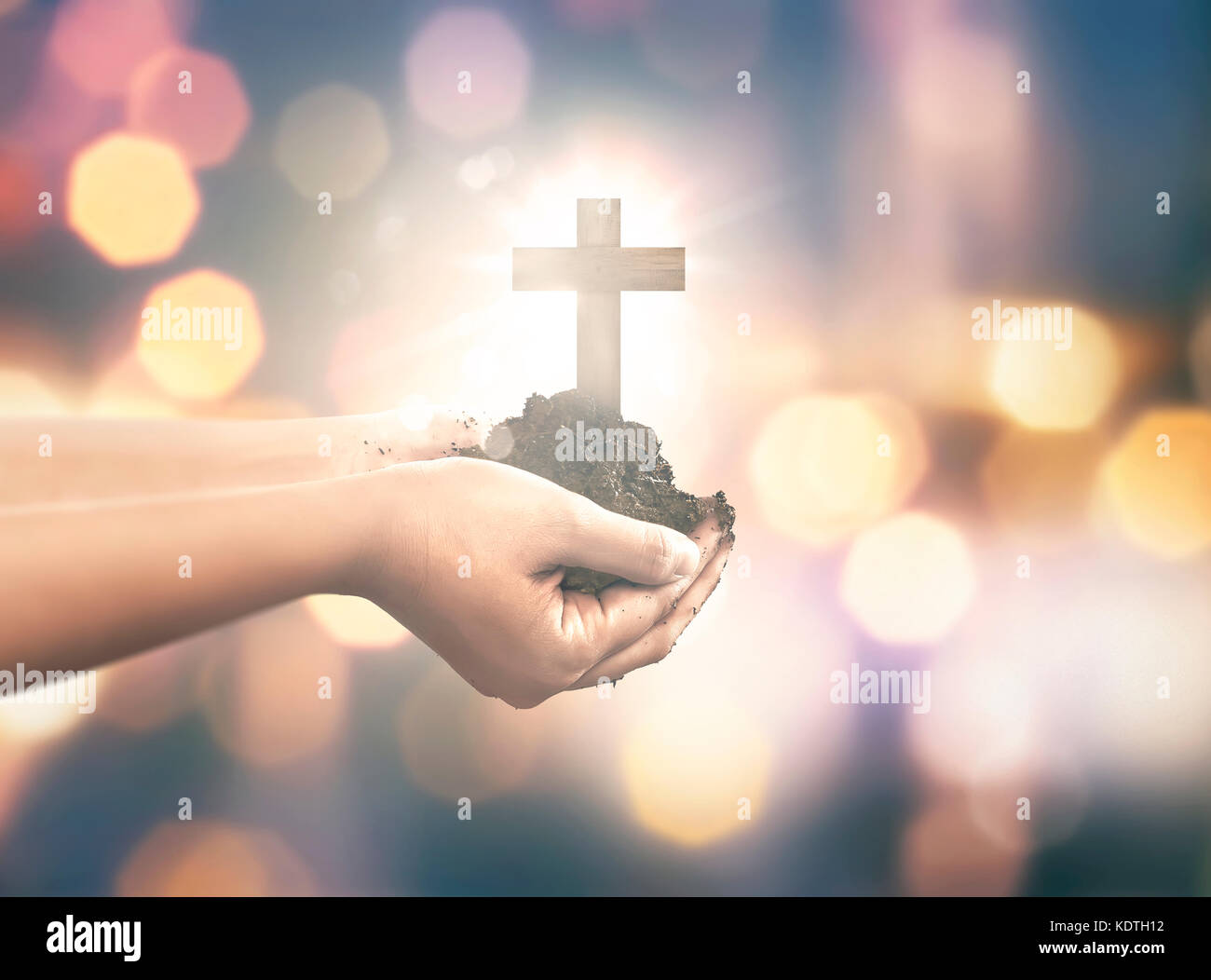 Mano umana tenendo una croce cristiana con il terreno per la mano sopra la sfocatura sullo sfondo Foto Stock