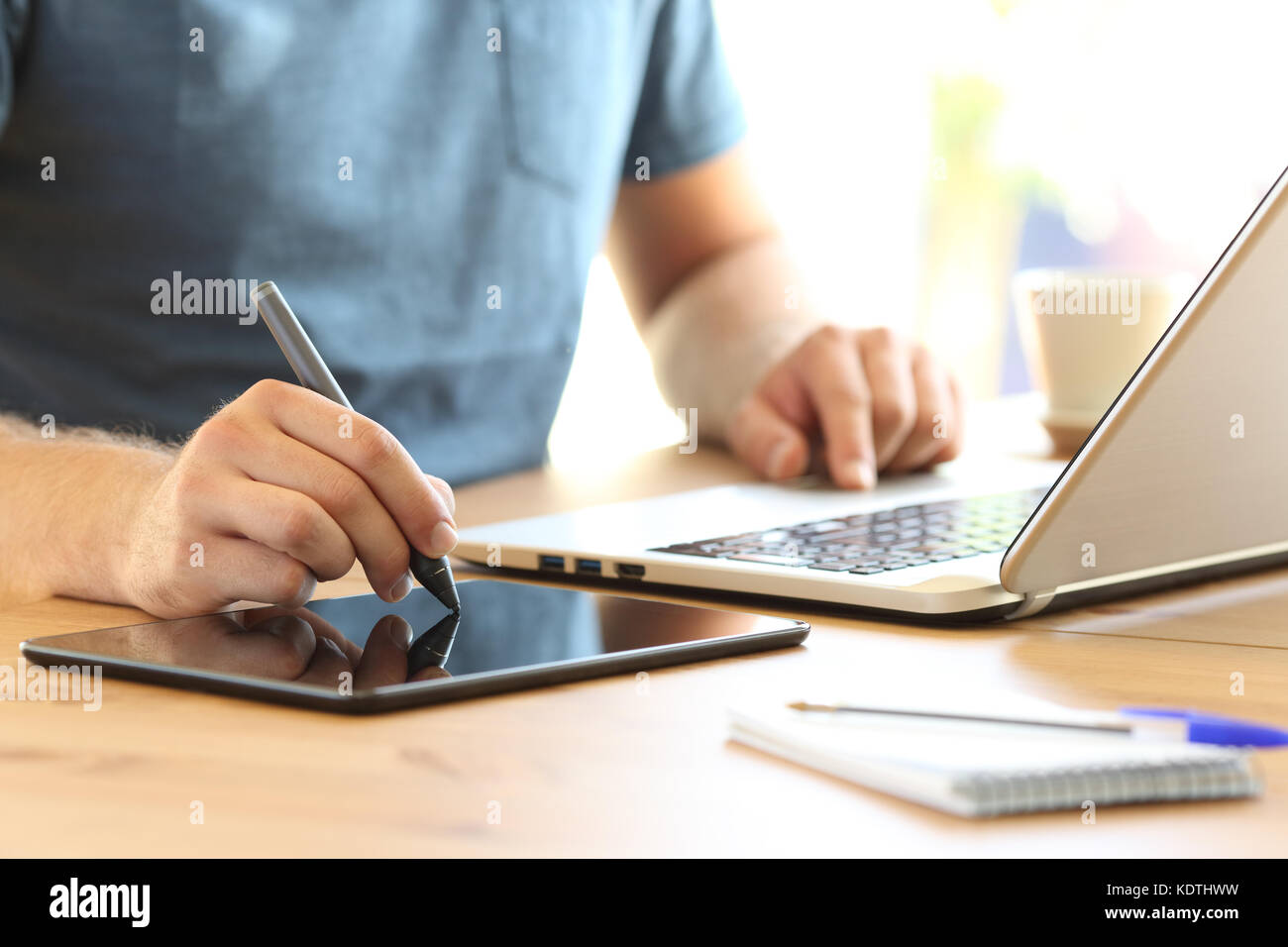 Close up di un uomo del disegno a mano con un display penna e un computer portatile su una scrivania a casa o in ufficio Foto Stock