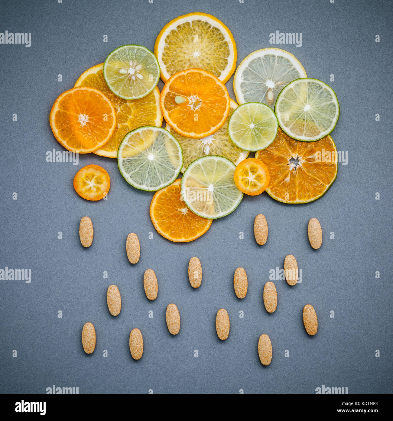 Cibi sani e il concetto di medicina. pillole di vitamina C e di agrumi in forma di nubi e pioggia. agrumi fettine di lime,arancio e limone Foto Stock