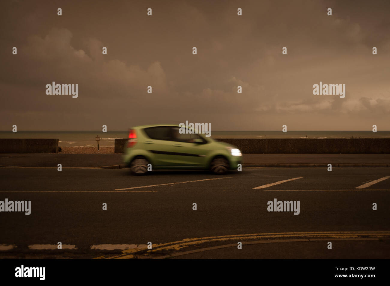 Il giorno si trasforma in notte come una unità auto lungo il lungomare di Littlehampton West Sussex, in Inghilterra. Il cielo si è oscurato e uno strano bagliore arancione è apparso nel bel mezzo della giornata. Le luci di strada è venuto su e i piloti hanno dovuto mettere i loro fari su. Rapporti dire il fenomeno è stato causato dalla ex uragano, Storm Ofelia, tirando in aria e polvere dall'Europa meridionale e in Africa. Foto Stock