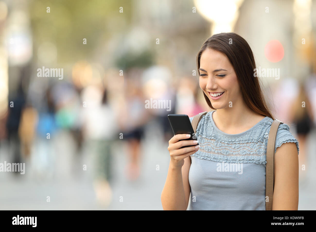 Unica donna felice utilizzando uno smart phone guardando sul contenuto della linea permanente sulla strada Foto Stock