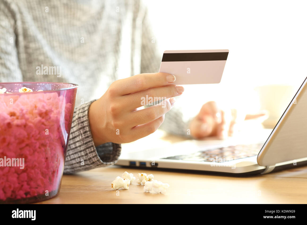 In prossimità di una donna mano acquisto pay per view on line con carta di credito e un computer portatile su un tavolo a casa Foto Stock