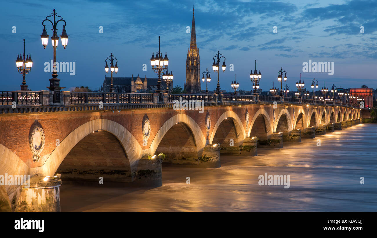 Pont de Pierre che attraversano il fiume Garonne al crepuscolo con Basilique Saint-Michel oltre, Bordeaux Aquitania, Francia Foto Stock