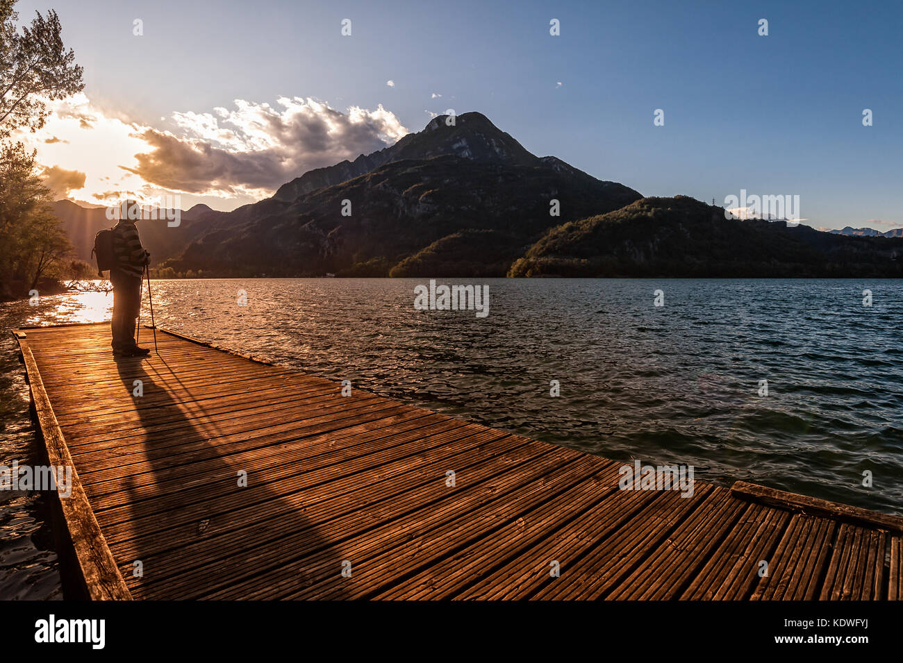 Escursionista in piedi sul dock fine sul lago. Tramper guardando il tramonto sul lago. Foto Stock