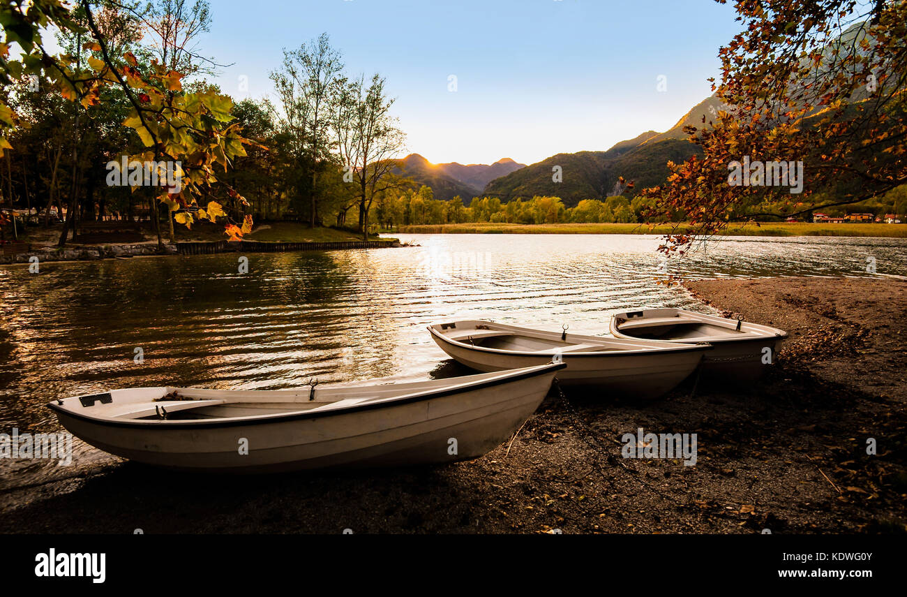 Tre barche sulla riva del lago al tramonto in autunno. Foto Stock