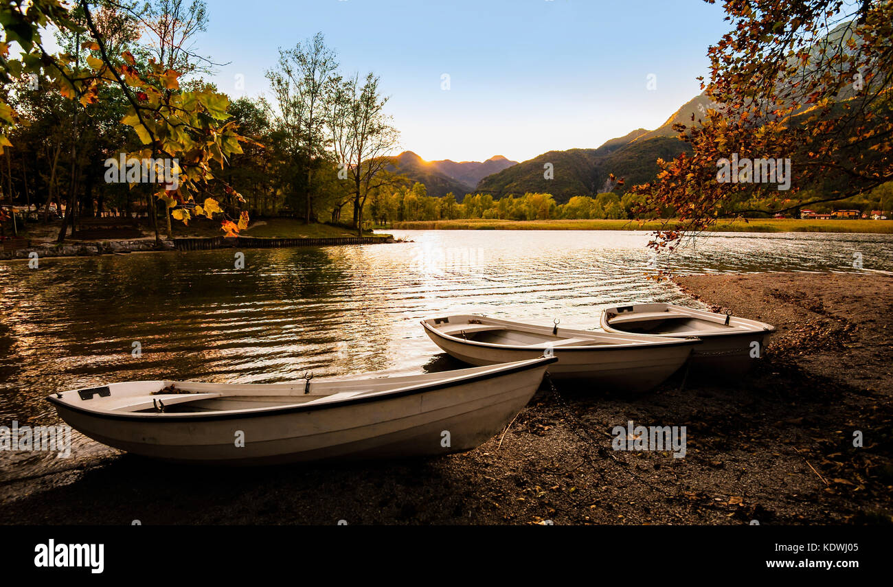 Tre barche sulla riva del lago al tramonto in autunno. Foto Stock