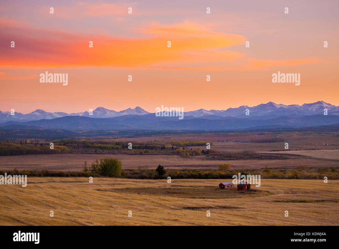 Le nuvole catturano il tramonto sopra le colline pedemontane a ovest di Calgary, dove vengono raccolti i campi. Foto Stock