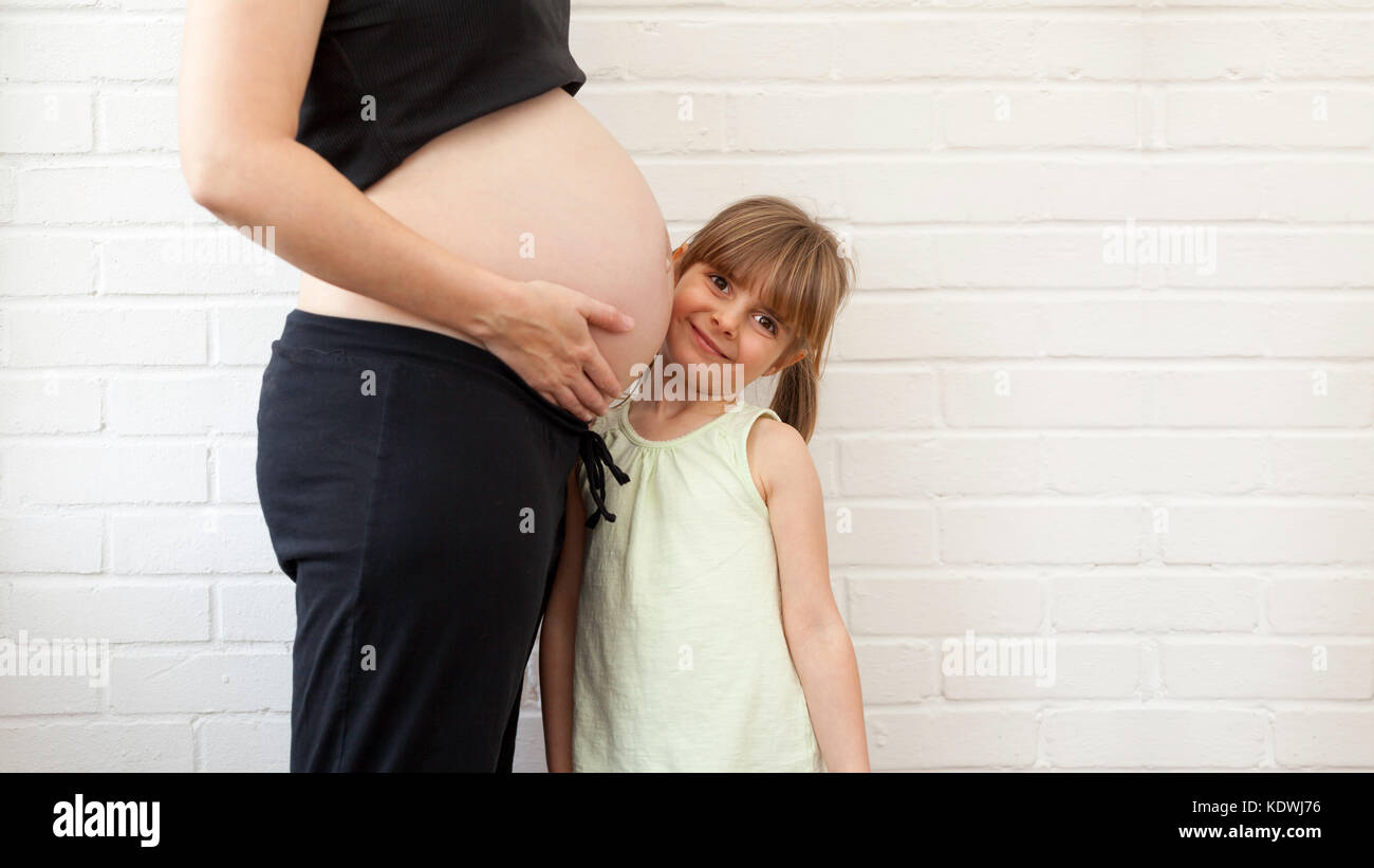 Madre in attesa che mostra nudo ventre in gravidanza o protuberanza al  giovane sorridente bambina. Mamma e figlia ritratto. La famiglia felice e  salute della donna in pregn Foto stock - Alamy