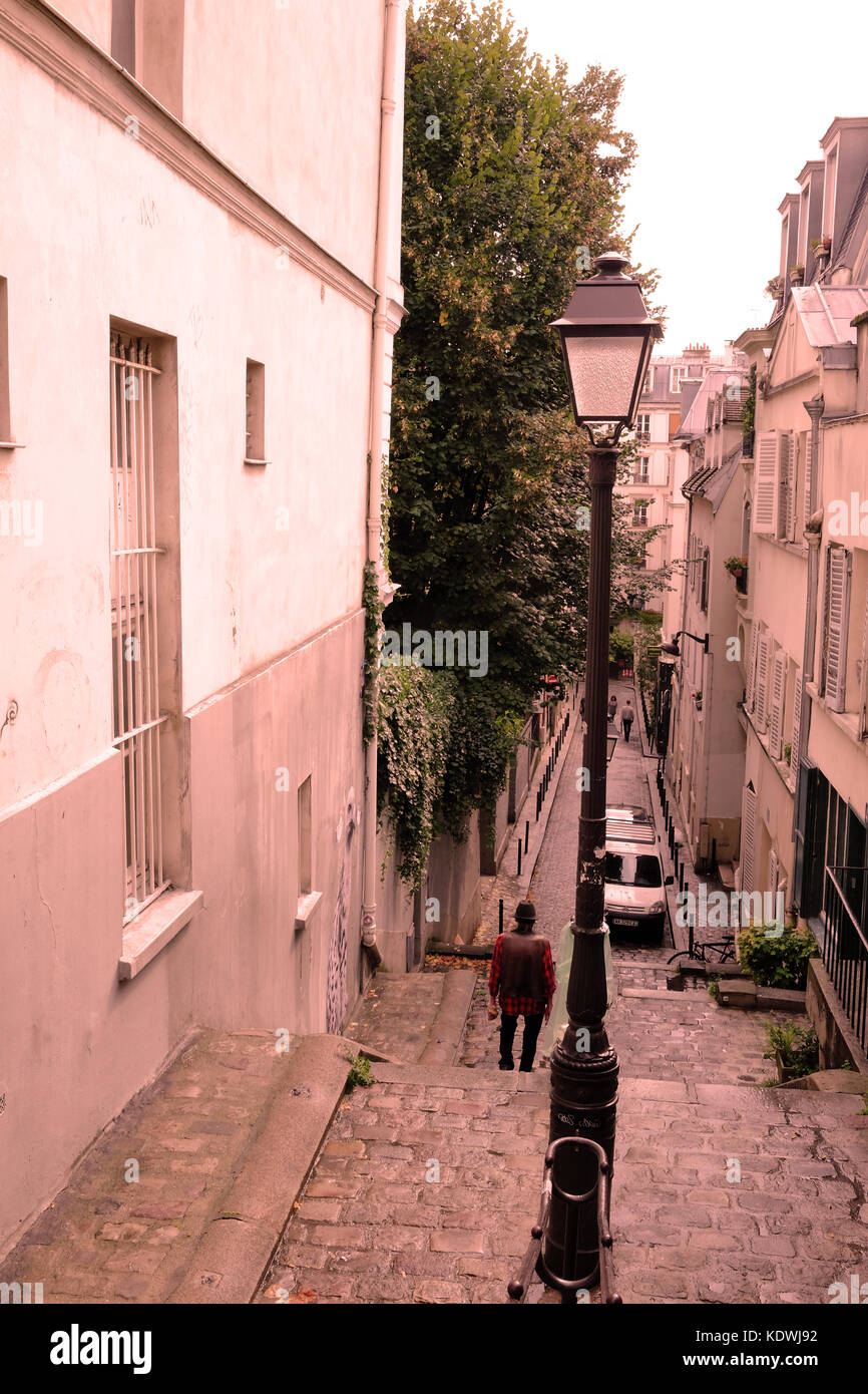 Un locale francese uomo cammina verso il basso di una delle molte scale in pietra di Montmartre a Parigi Foto Stock