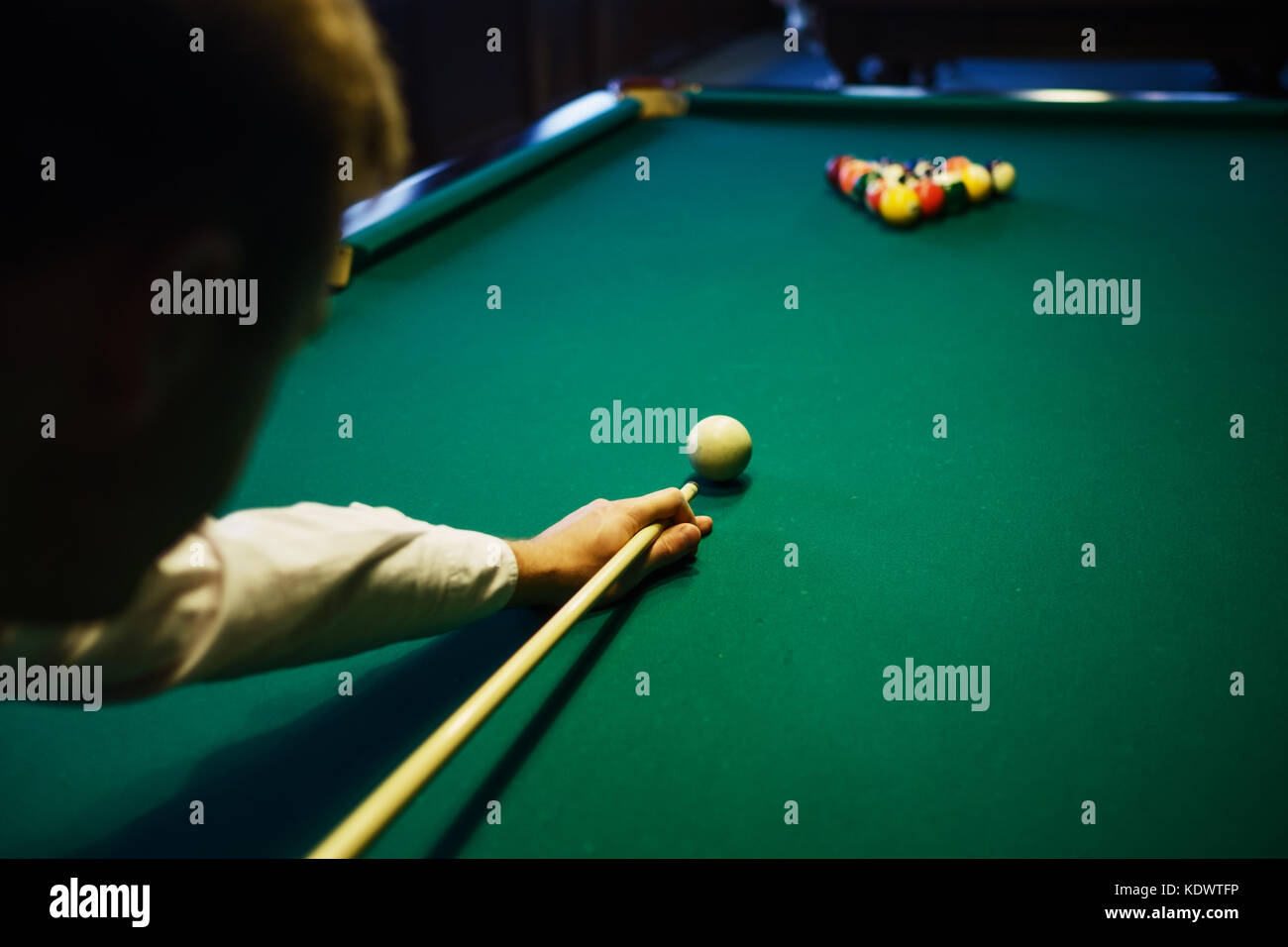 Biliardo americano. L'uomo giocando a biliardo, snooker. Il giocatore si prepara a sparare e a colpire la bilia battente. Foto Stock