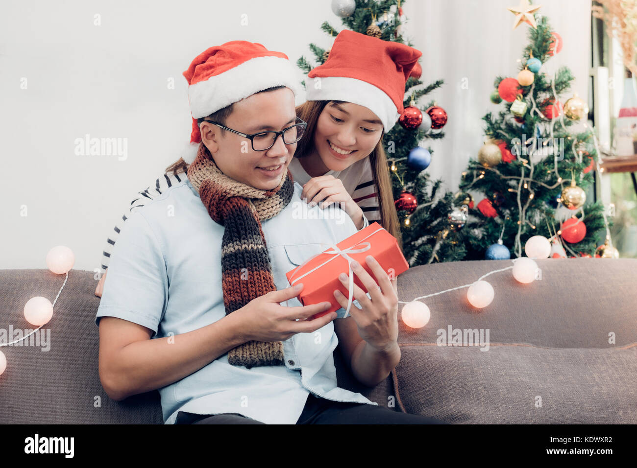 Asia amanti giovane,ragazza sorpresa fidanzato dando il regalo di Natale al  divano con il natale decorazione albero a house party,holiday celebrando  mari Foto stock - Alamy