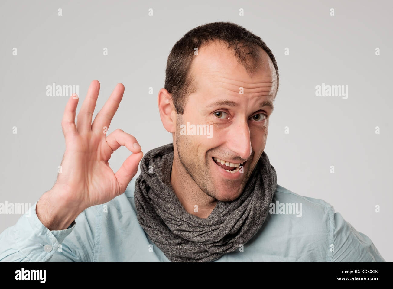 Felice l'uomo spagnolo mostra OK contro uno sfondo grigio. Foto Stock