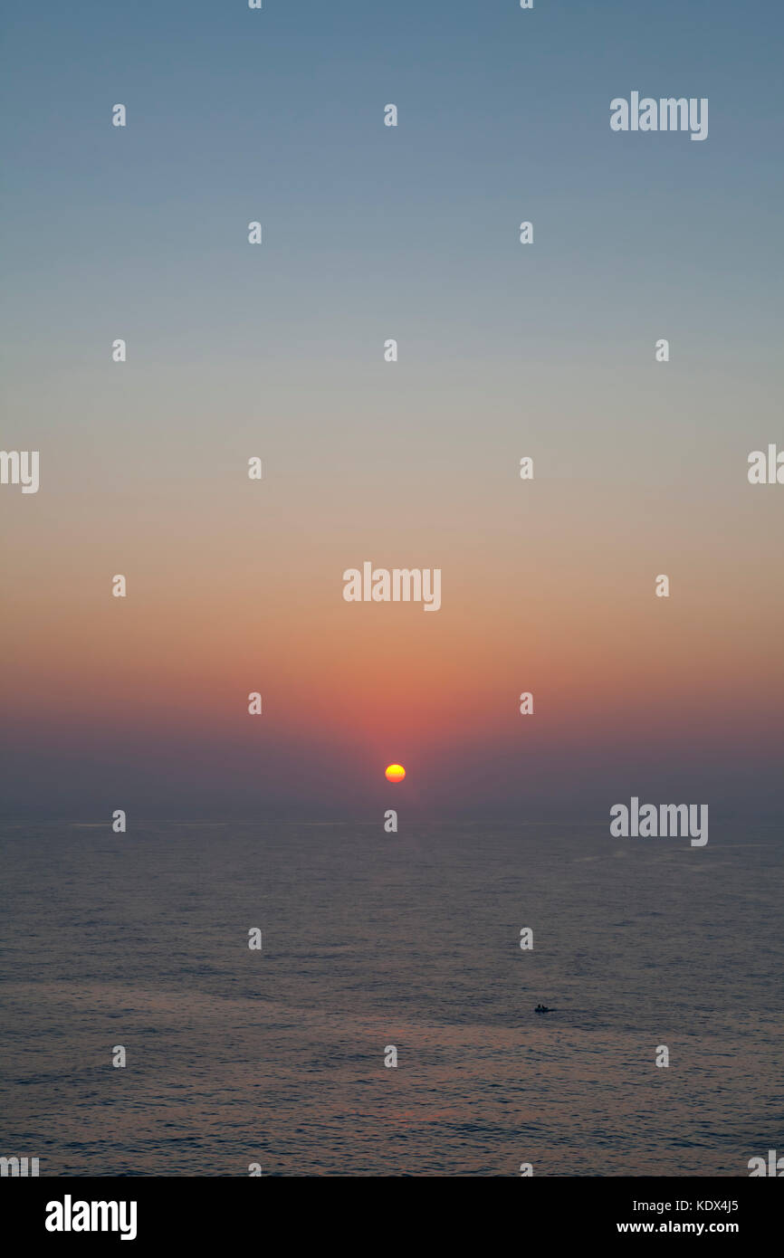 Il sole sorge sopra le calme acque del mar mediterraneo a Malta Foto Stock