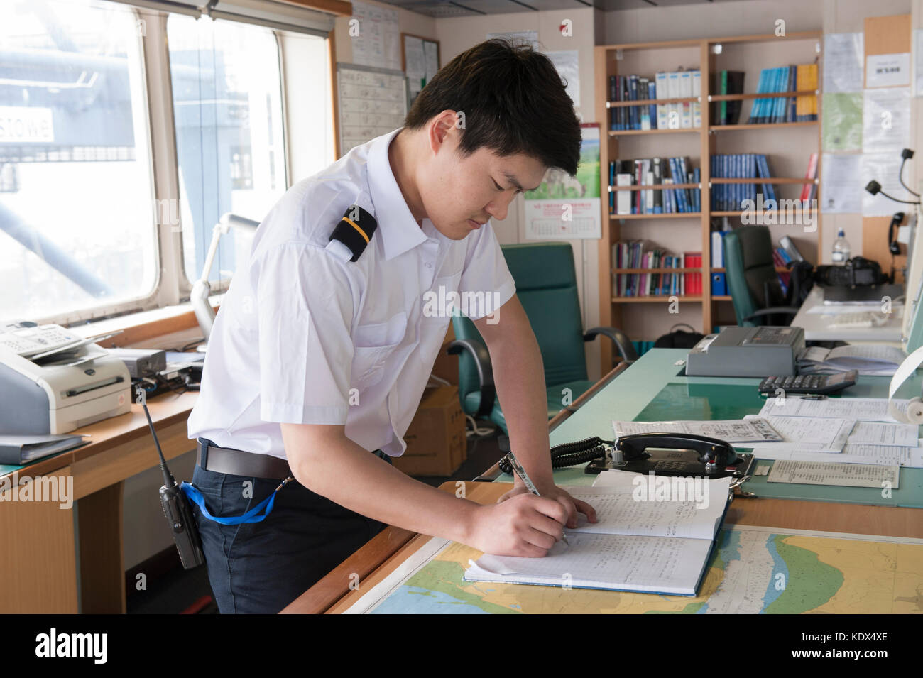 Un funzionario la scrittura di note di navigazione su una nave mercantile Foto Stock