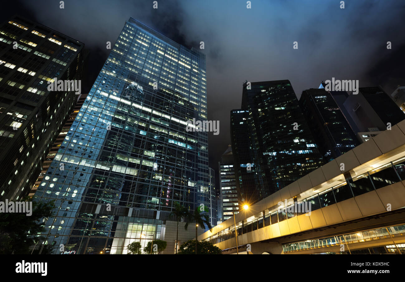 Notte cityscape con grattacieli sotto il cielo nuvoloso scuro, alto-aumento edifici per uffici a Hong kong city Foto Stock