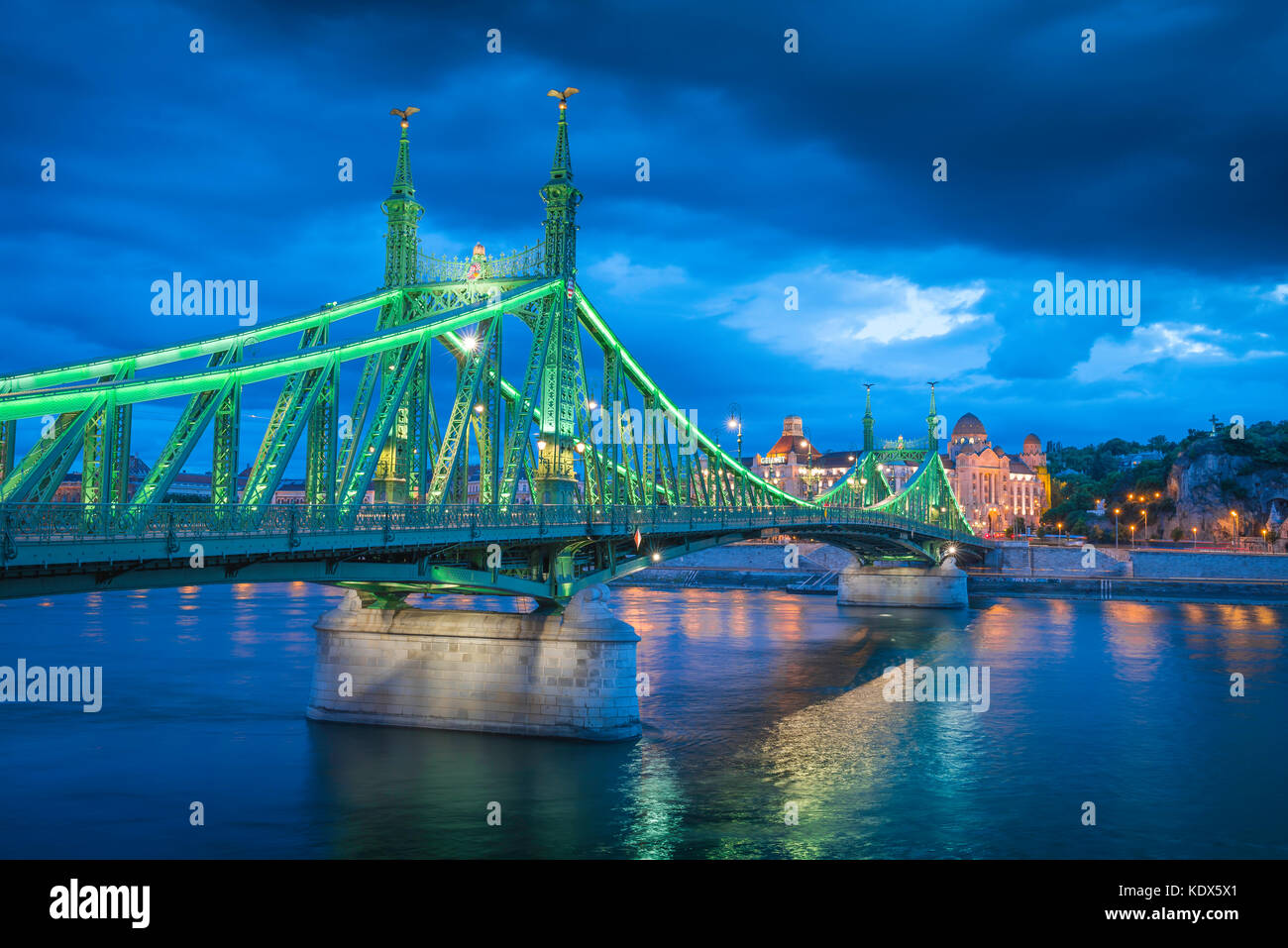 Il Fiume Danubio Budapest, il ponte Szabadsag illuminata di notte che attraversano il fiume Danubio con il Gellert Hotel in distanza, Budapest, Ungheria. Foto Stock