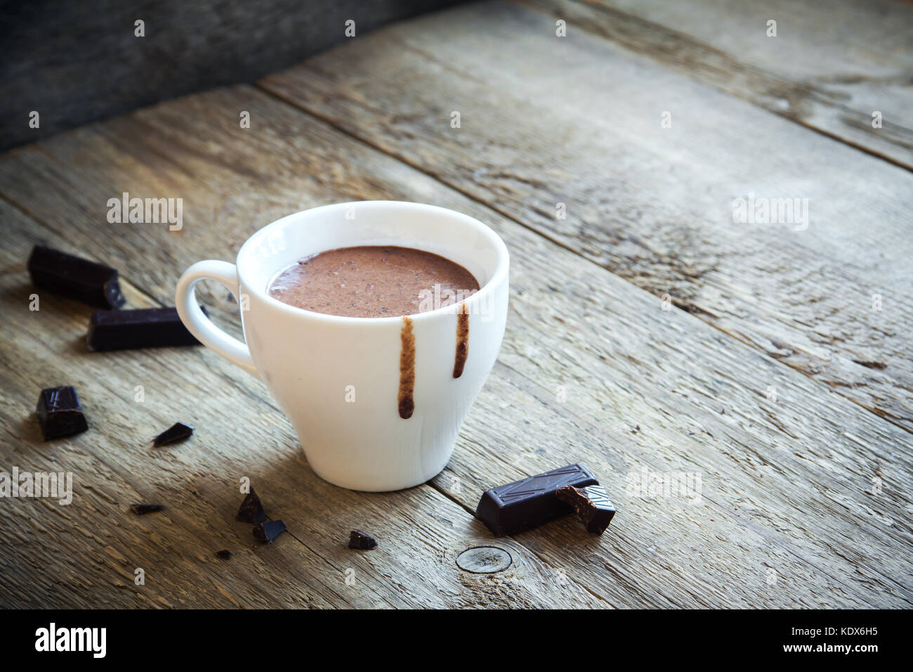 Cioccolata calda e pezzetti di cioccolato su legno rustico sfondo. in casa cioccolata calda bevanda per le vacanze di Natale ed invernali. Foto Stock