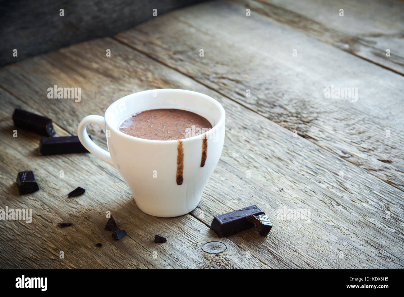 Cioccolata calda e pezzi di cioccolato su fondo rustico in legno. Bevanda al cioccolato caldo fatta in casa per Natale e le vacanze invernali. Foto Stock
