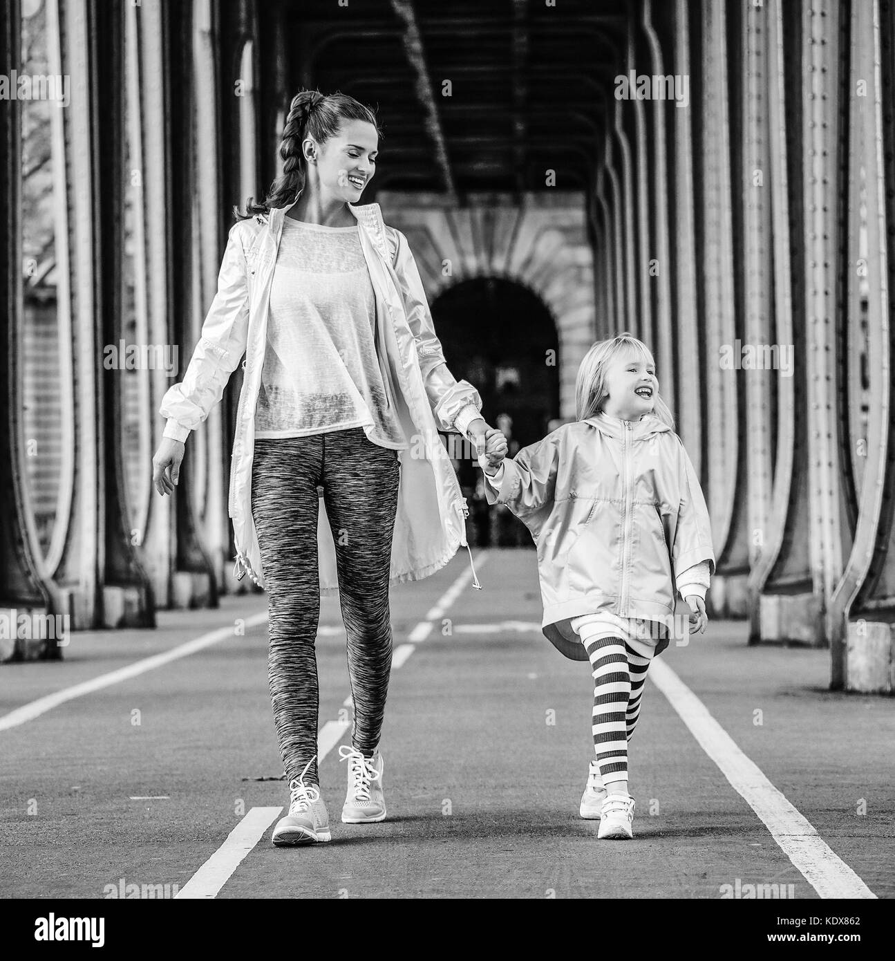 Anno fit & hip a Parigi. a piena lunghezza Ritratto di sorridere attivo la madre e il bambino in stile sport vestiti sul Pont de bir-hakeim bridge in paris go Foto Stock