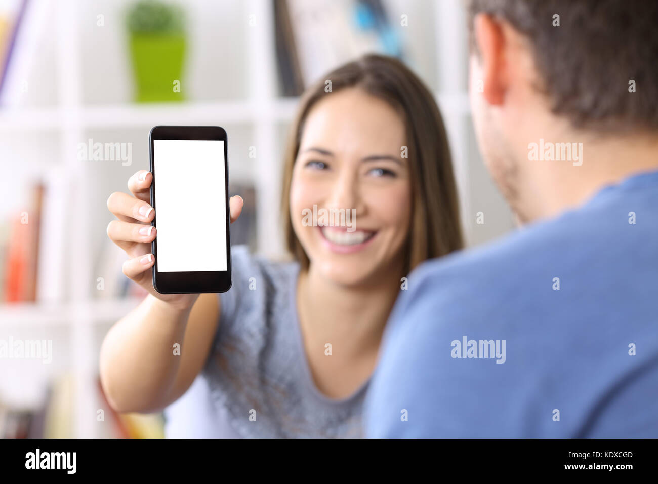 La donna che mostra un telefono intelligente schermo per un amico a casa Foto Stock