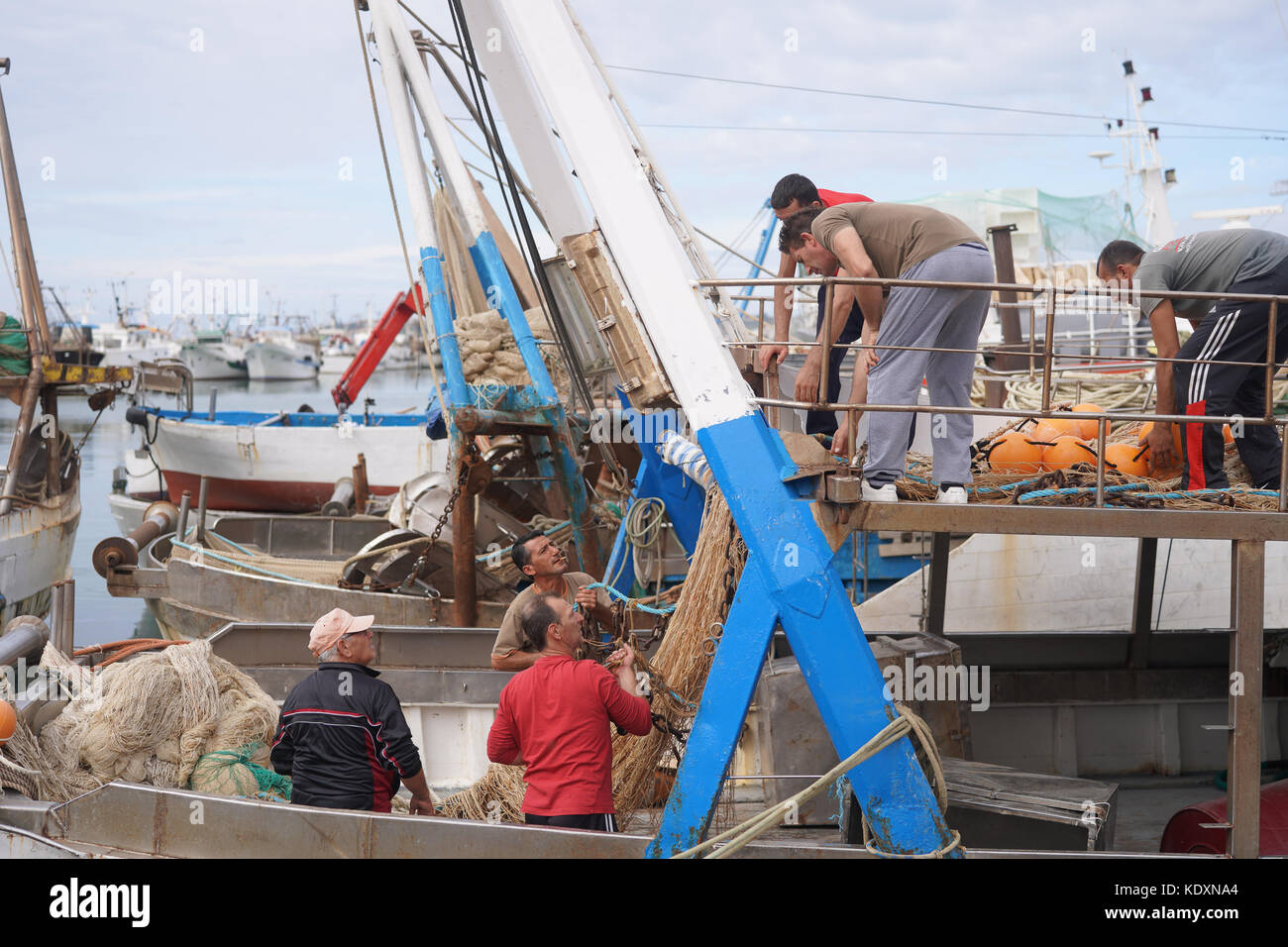 I pescatori riassettavano le reti durante un mese di embargo di pesca nel porto di Sciacca. da una serie di foto di viaggio in Sicilia, Italia. data foto: mar Foto Stock