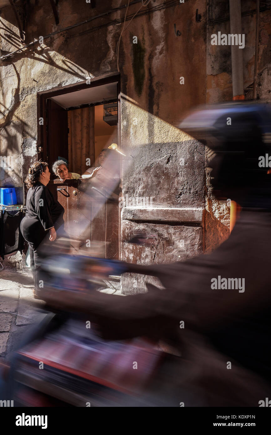 Un uomo su un ciclomotore rides ultimi tre locali avente una chat tra i vicoli di palermo. da una serie di foto di viaggio in Sicilia, Italia. data foto: mo Foto Stock