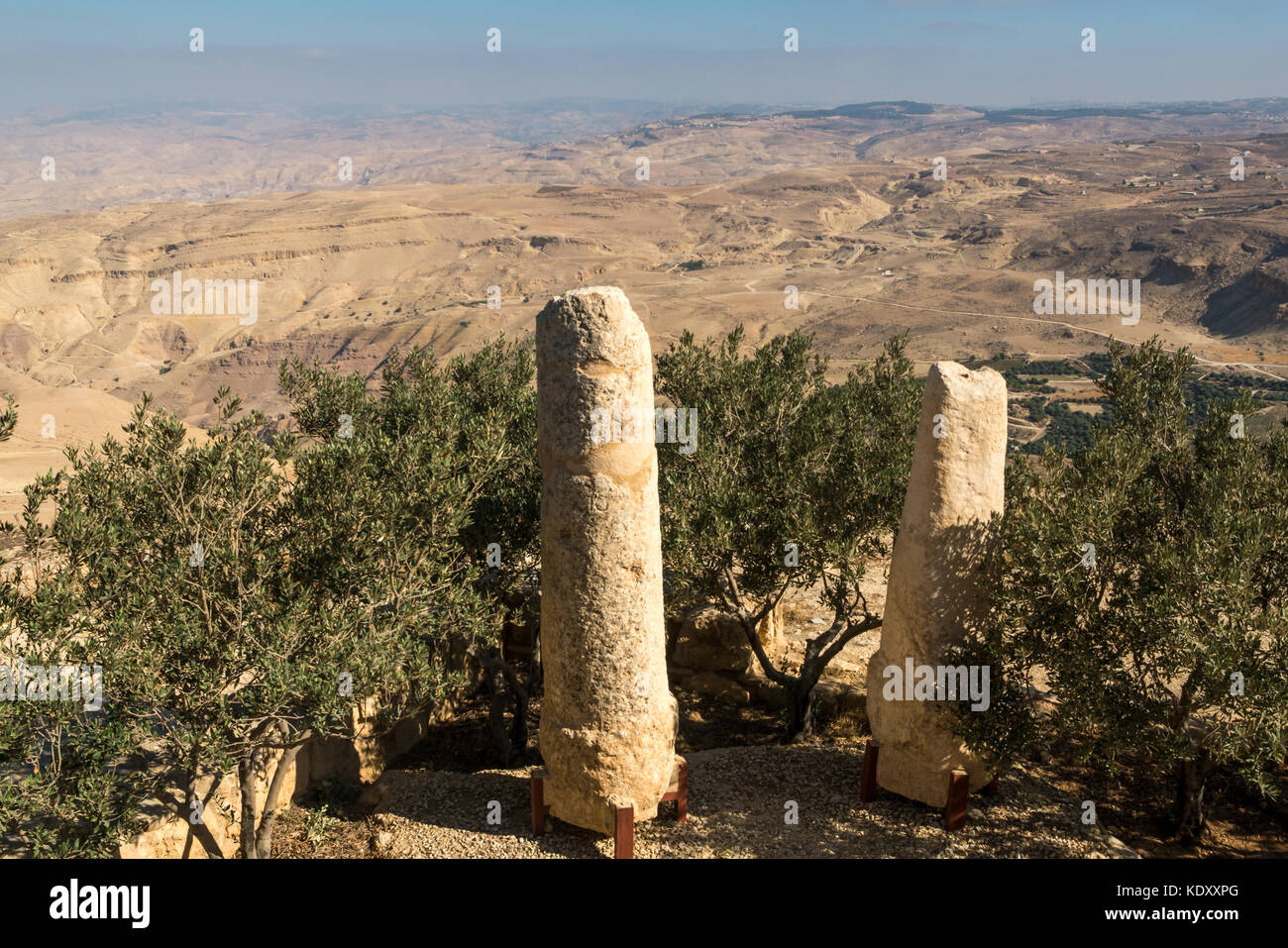 Miliare romano pilastri in primo piano, che rivestito l'antica via di pellegrinaggio tra Gerusalemme e il Monte Nebo, Giordania, che si affaccia su di una vallata desertica Foto Stock
