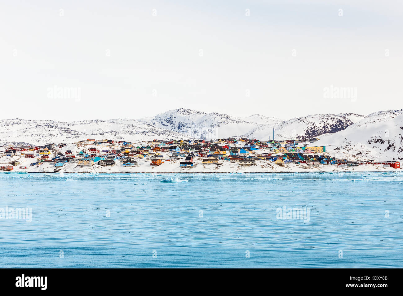 Arctic panorama cittadino con coloratissime case inuit sulle colline rocciose coperte di neve con la neve e la montagna in background, ilulissat Foto Stock