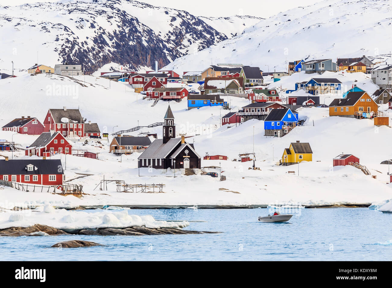 Insediamento artico con coloratissime case inuit sulle colline rocciose coperte di neve con la neve e la montagna in background, ilulissat Foto Stock