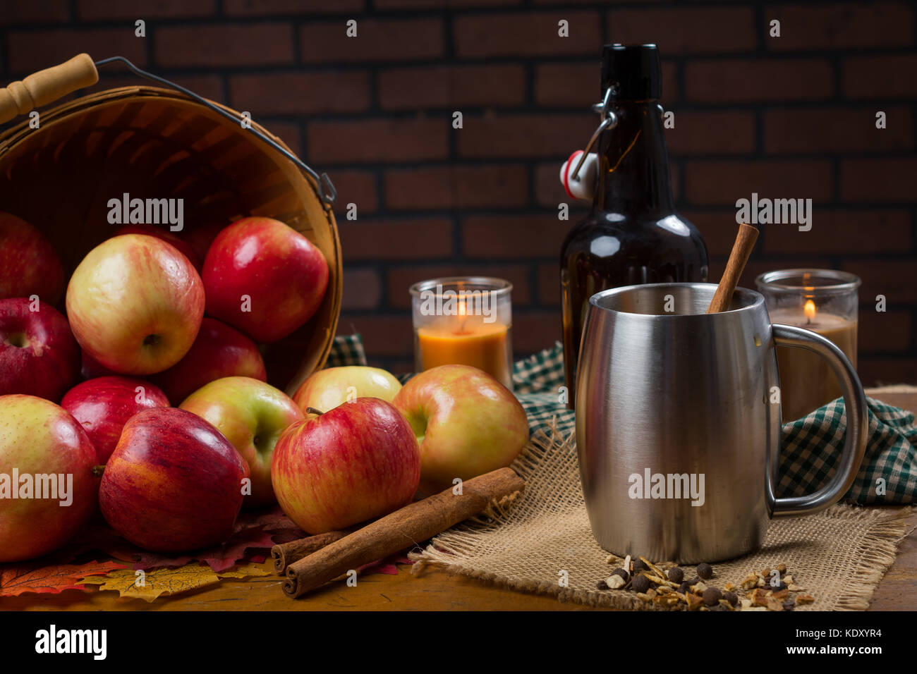 Cup con il sidro di mele e di stecca di cannella. arredamento rustico e mele intorno ad esso. Foto Stock