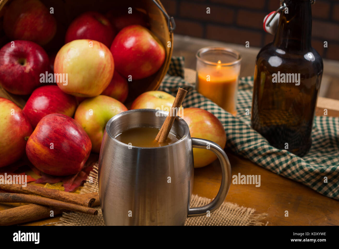 Argento la tazza con il sidro di mela. versato del cesto di mele in background lungo con decorazioni rustiche. Foto Stock