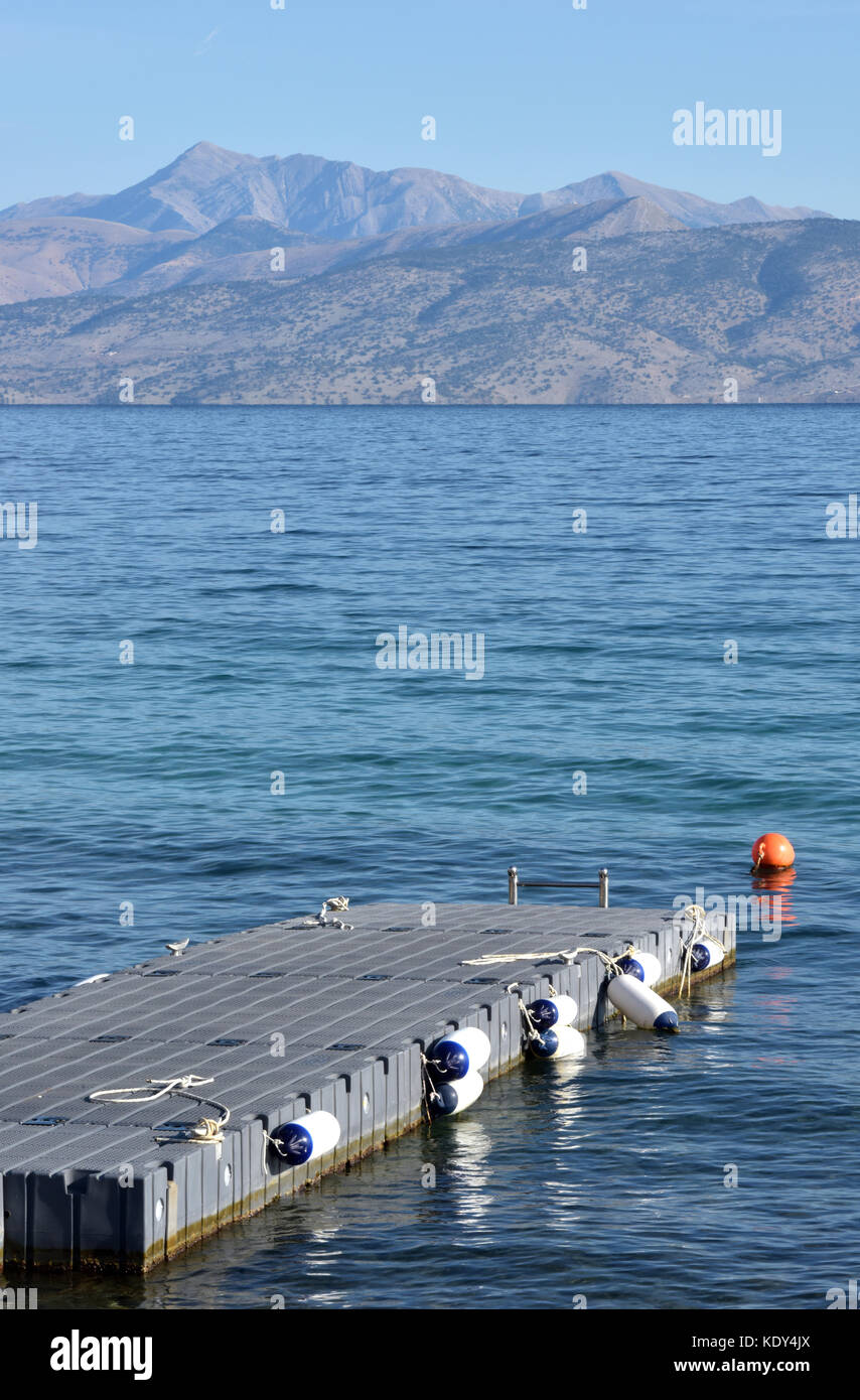 Un pontone galleggiante o molo sulla costa a Kassiopi Corfù, Grecia sul mare guardando fuori verso le montagne dell'albania in background. Foto Stock