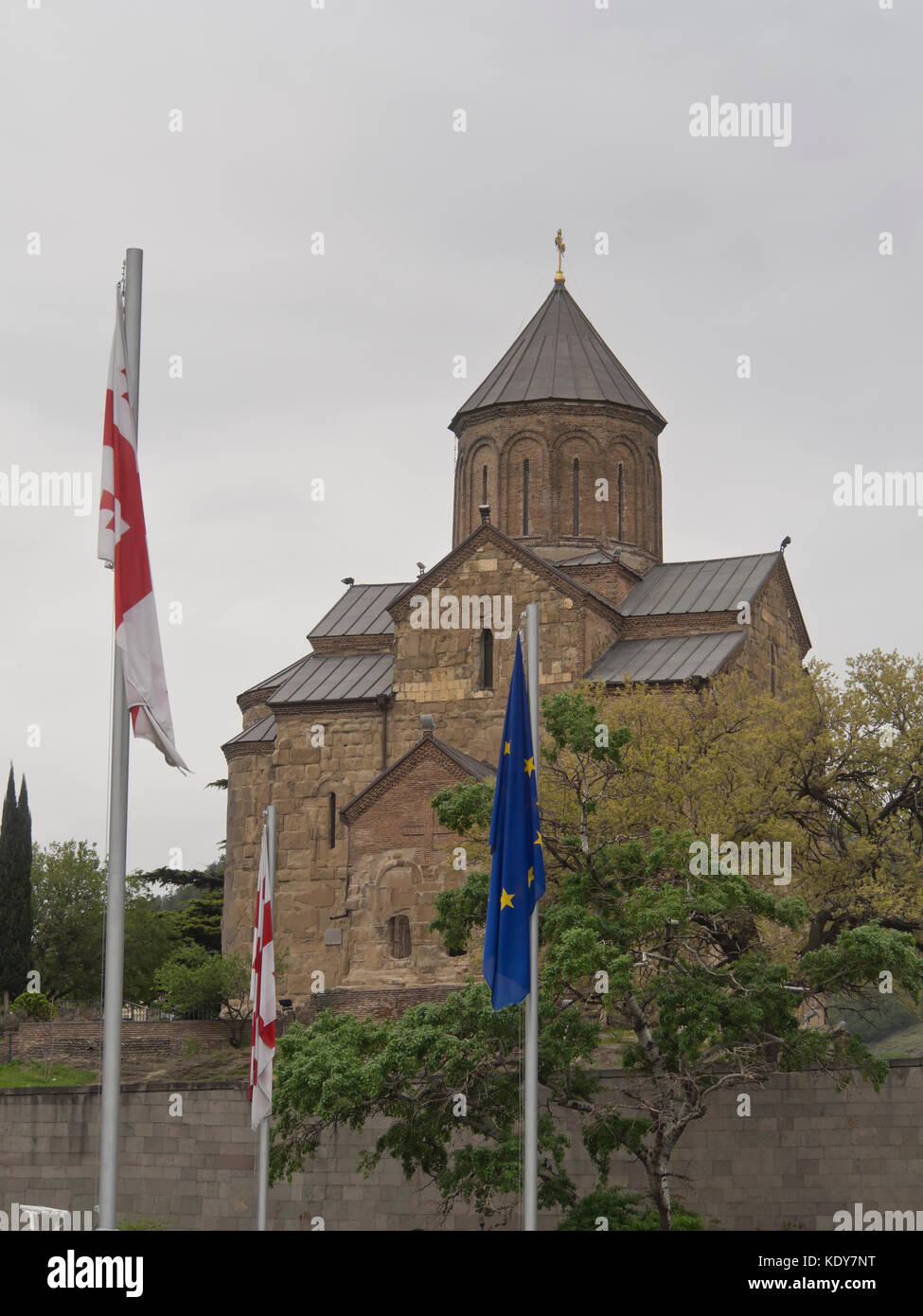 Vergine Maria Chiesa di Metekhi a Tbilisi, Georgia su una collina sopra la piazza Europa, con georgiano e bandiera UE Foto Stock