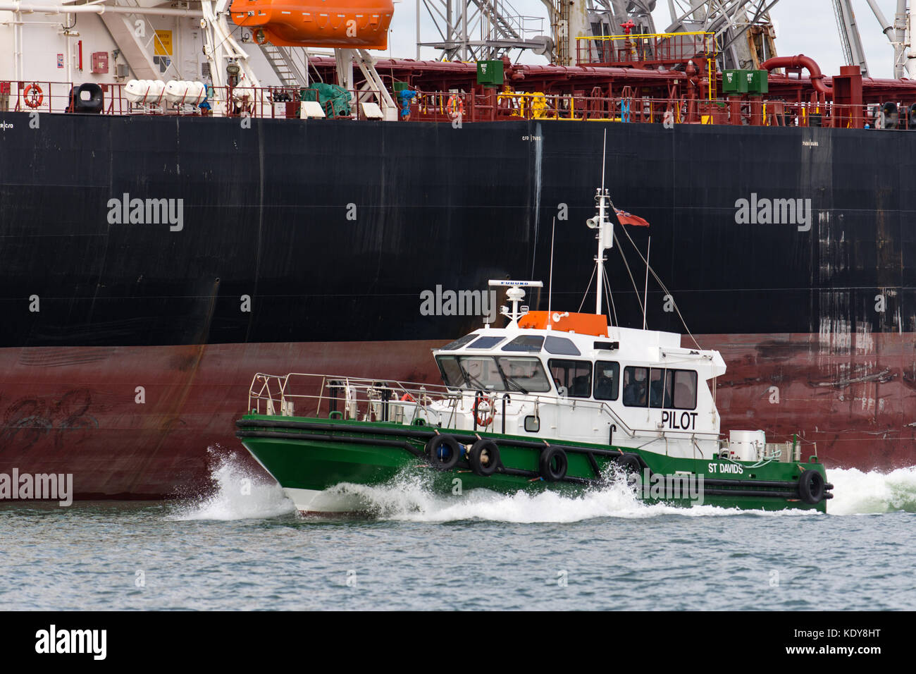 Barca pilota St Davids passando un ormeggiato tanked in Milford haven, Pembrokeshire Foto Stock