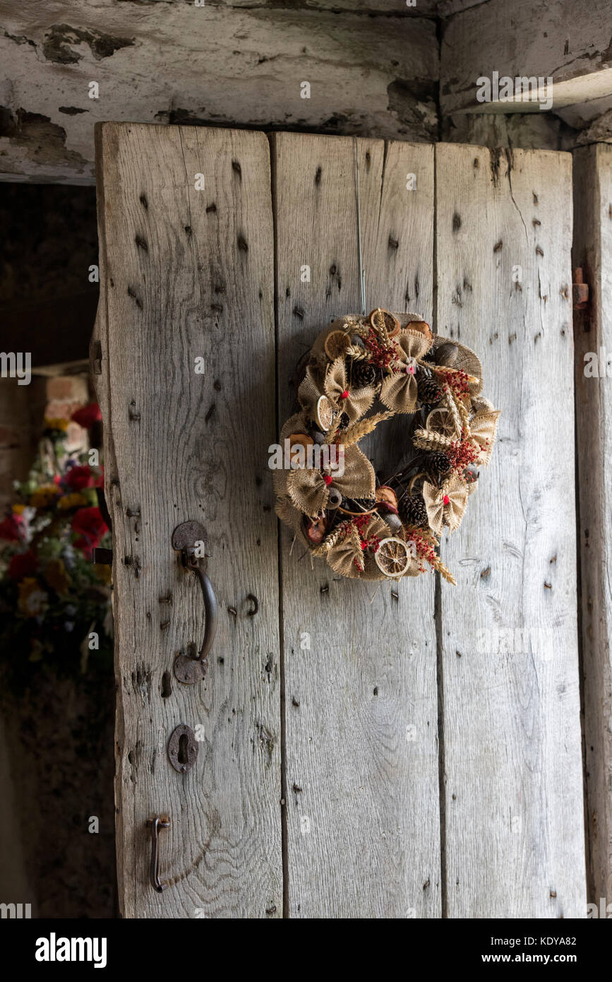 Rustico autunnale harvest festival corona su una vecchia porta in legno di quercia a Weald and Downland Open Air Museum, Campagna autunno mostra, Singleton, Sussex, Inghilterra Foto Stock