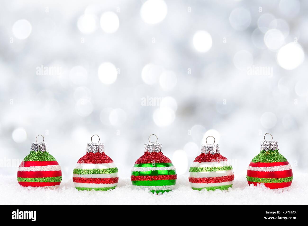 Rosso, verde e bianco Natale ornamenti nella neve con il luccichio sfondo color argento Foto Stock Rosso, verde e bianco Natale ornamenti nella neve con il luccichio sfondo color argento Foto Stock