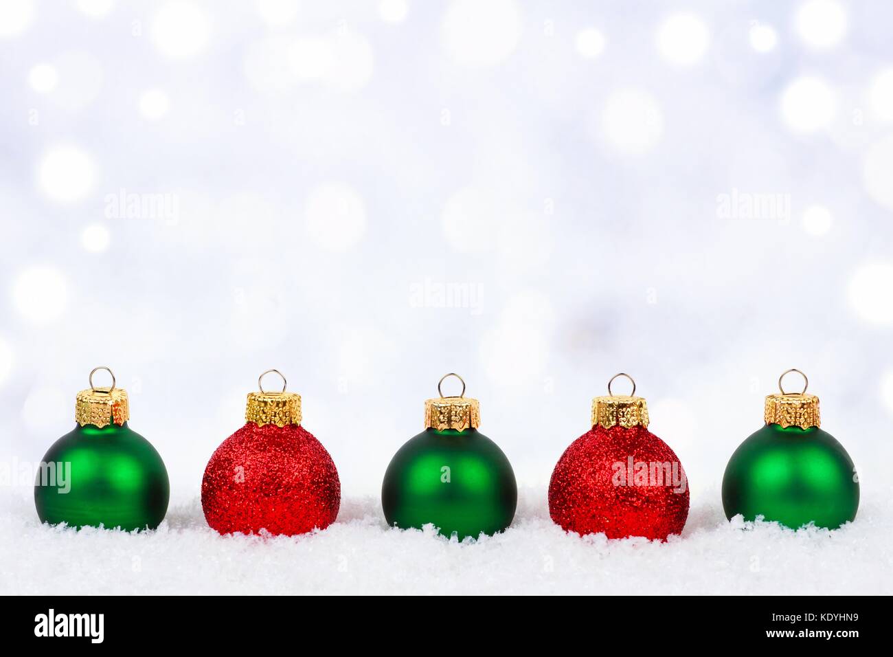 Rosso e verde di Natale ornamenti nella neve con il luccichio sfondo color argento Foto Stock Rosso e verde di Natale ornamenti nella neve con il luccichio sfondo color argento Foto Stock