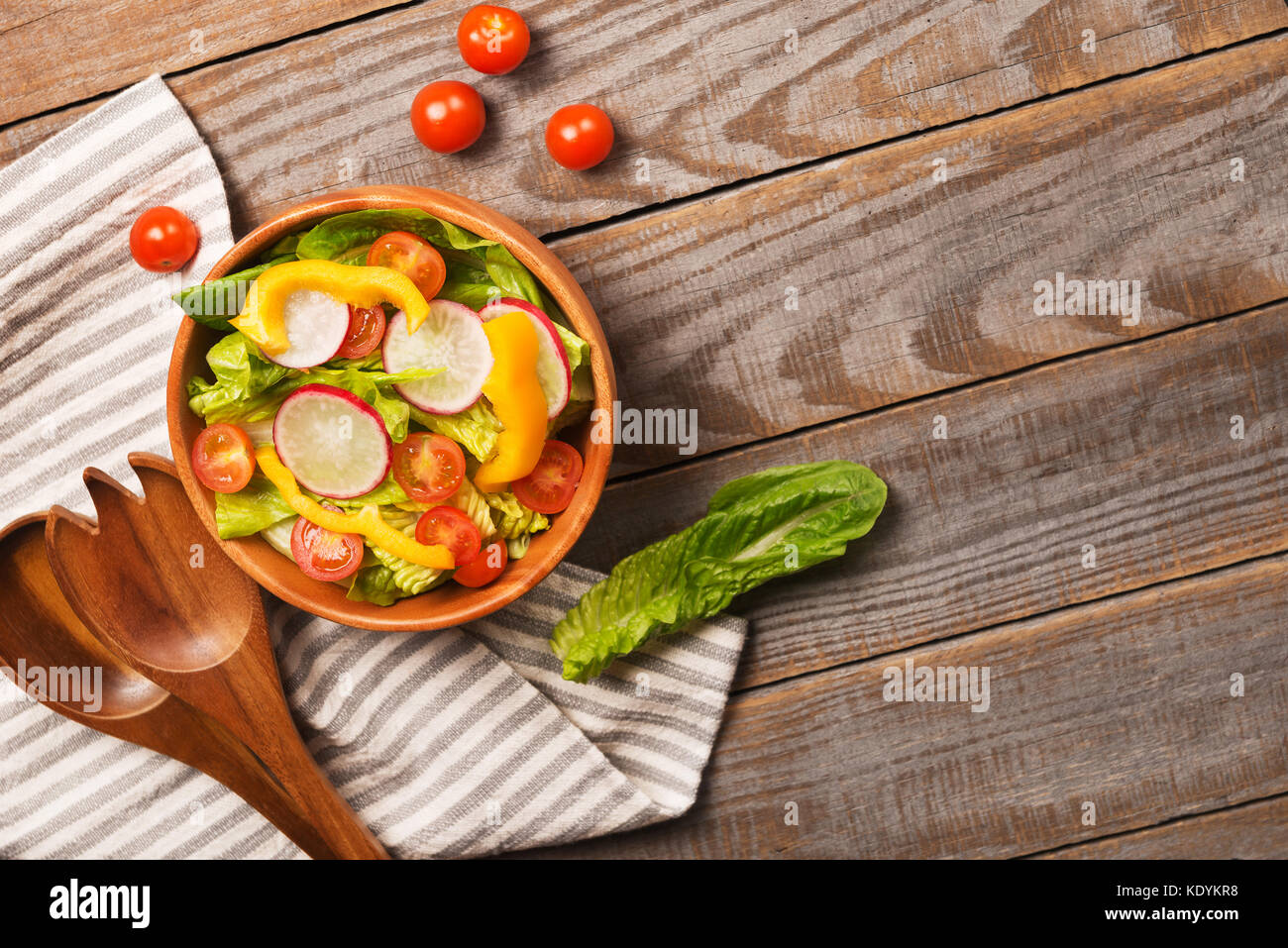Fresca insalata sana con cos lattuga, pomodori ciliegini, peperone, Rafano su sfondo di legno vista superiore con copyspace.cibo e salute. Foto Stock